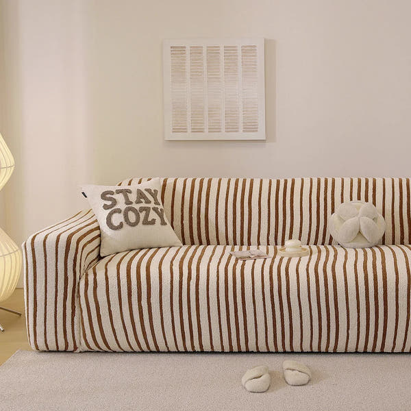Caramel brown striped stretch sofa cover styled in a warm living room with a cushion