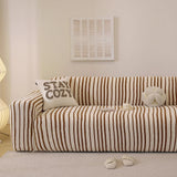 Caramel brown striped stretch sofa cover styled in a warm living room with a cushion