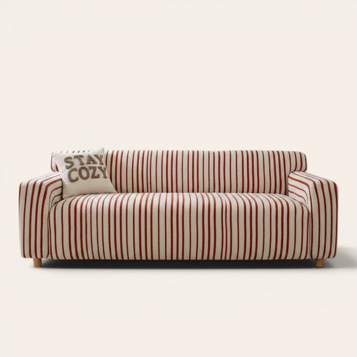 Crimson red striped sofa cover on a three-seat sofa with matching cushions, front view on ivory