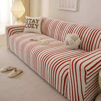 Corner detail of the crimson red striped sofa cover wrapping the armrest near a soft lamp