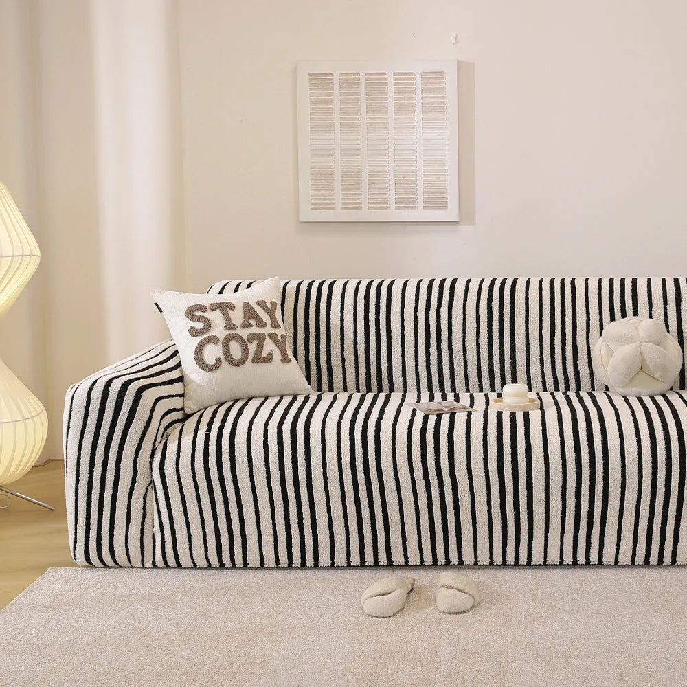 Midnight black striped stretch sofa cover styled in a bright living room with a cushion