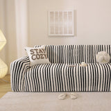 Midnight black striped stretch sofa cover styled in a bright living room with a cushion