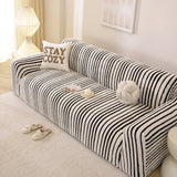 Angled view of the midnight black striped sofa cover draping over the seat and armrest