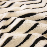 Corner detail of the midnight black striped sofa cover wrapping the armrest in a sunlit room