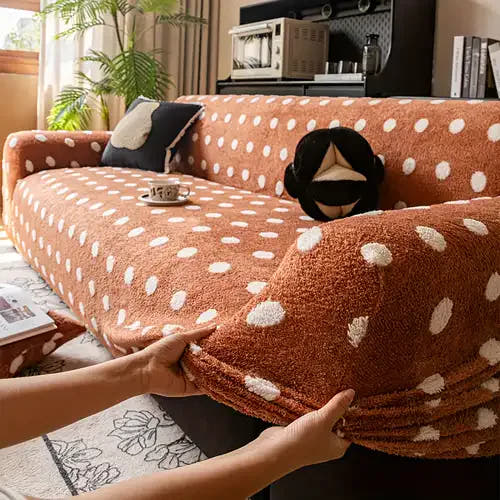 Hands smoothing the caramel teddy polka dot stretch sofa cover over the armrest in a sunlit living room