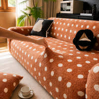 Caramel teddy polka dot sofa cover being adjusted across the seat in a bright living room