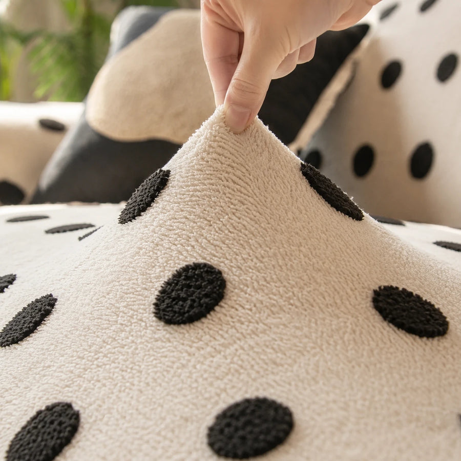 Hand lifting the stretchy cream black teddy sofa cover to show its raised black dots