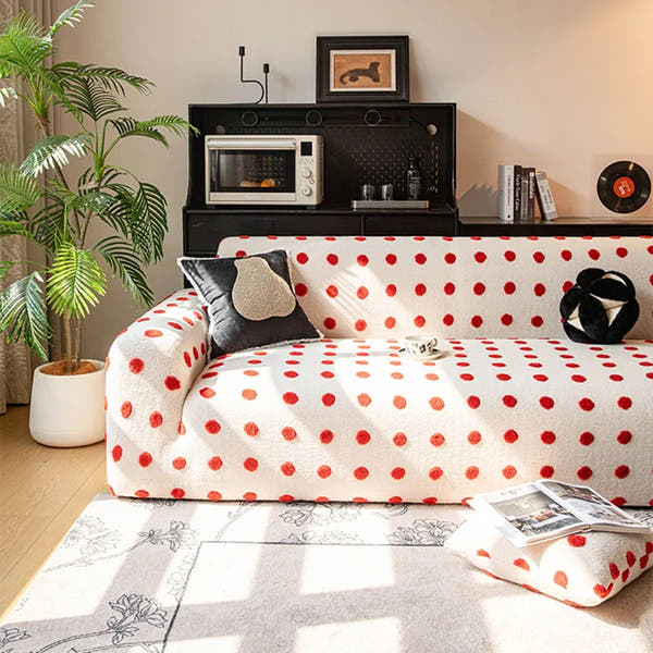 Cream red teddy sofa cover styled in a cozy living room with a dark cushion and a tall plant