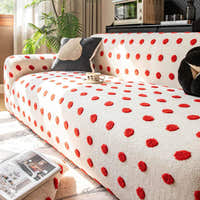 Sunlit angled view of the cream red teddy sofa cover with a dark accent cushion and coffee