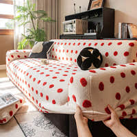 Hands fitting the cream red teddy sofa cover over the armrest to show its stretch