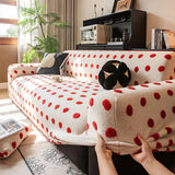Hands fitting the cream red teddy sofa cover over the armrest to show its stretch