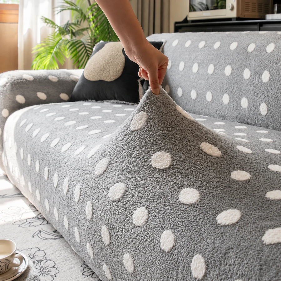 Hand lifting the stretchy grey snow teddy sofa cover to show its raised white dots
