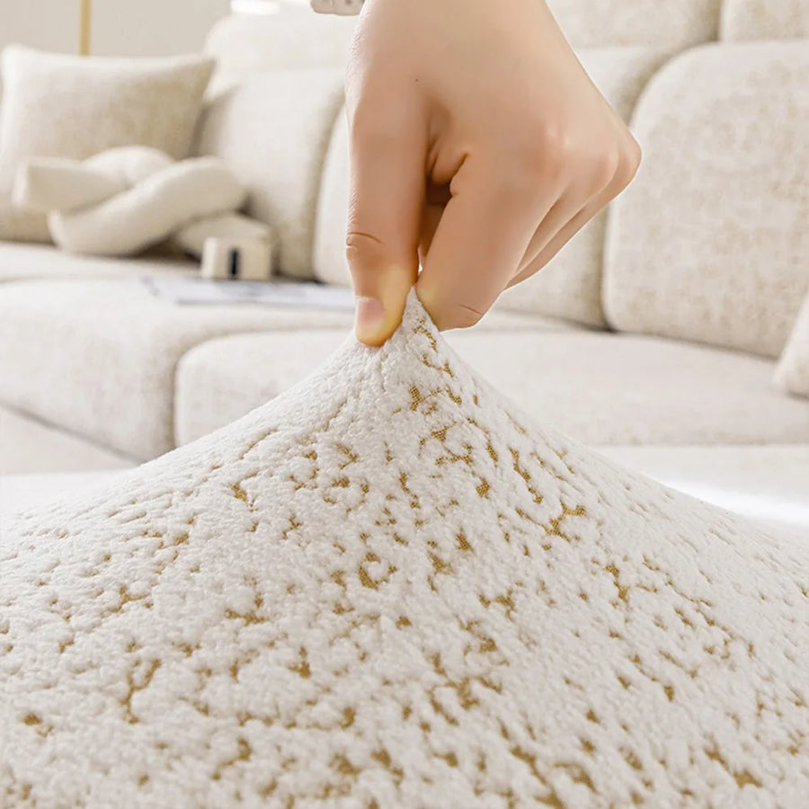 Hand lifting the stretchy sand gold teddy sofa cover to show its marbled sherpa pile