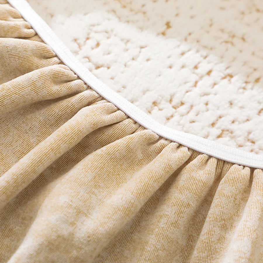 Detail of the elastic gathered hem on the sand gold teddy sofa cover for a fitted underside