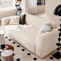 Angled living room view of the sand gold teddy sofa cover with grey cushions and a floor lamp