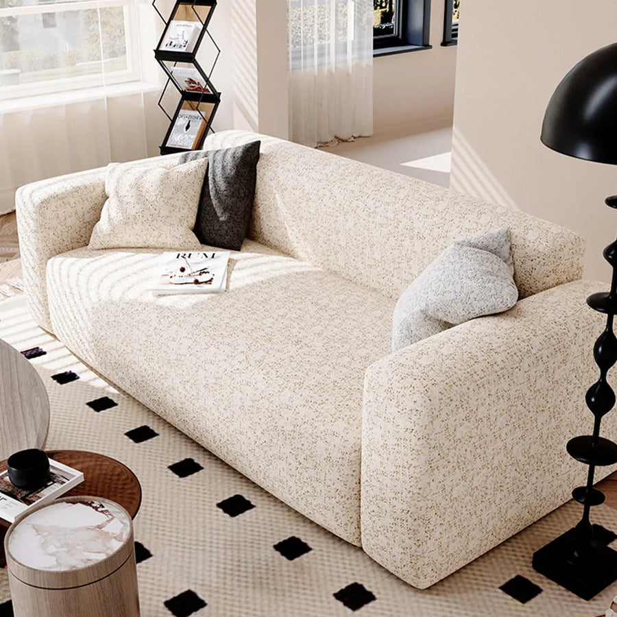 Angled living room view of the sand gold teddy sofa cover with grey cushions and a floor lamp