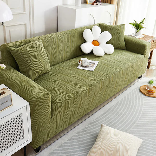 Sage green velvet sofa cover styled in a bright living room with a white flower cushion and coffee