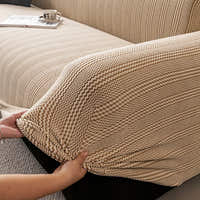 Hands smoothing the stretchy almond cream waffle sofa cover over the armrest corner