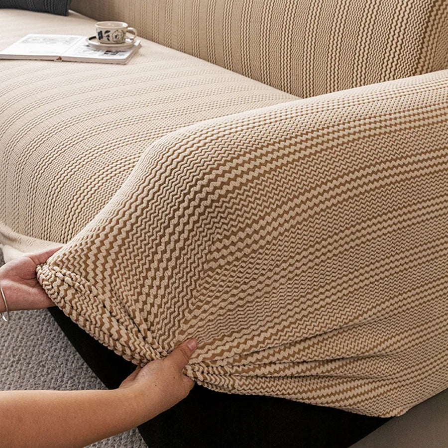 Hands smoothing the stretchy almond cream waffle sofa cover over the armrest corner