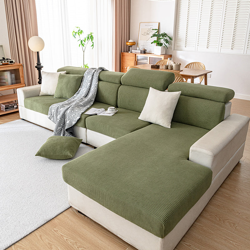 Olive green corduroy cushion covers on a cream sectional sofa, seen across a bright living room