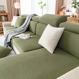 Close view of olive green corduroy seat and backrest covers with a white cushion and a patterned throw