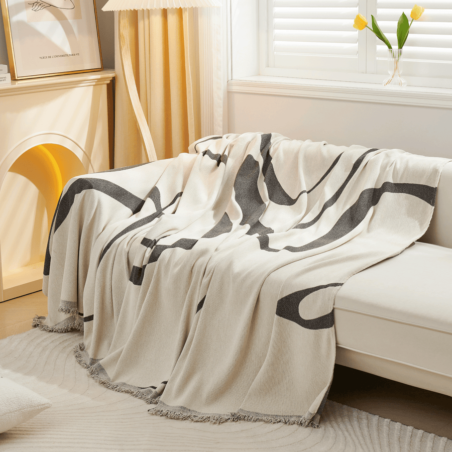 Angled cascade of the Abstract Haze Abstract Muse throw with fringed edge in a bright room