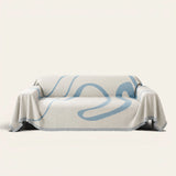 Abstract Muse sofa throw in Azure Flow draped over a couch, front view on ivory background with fringed edges