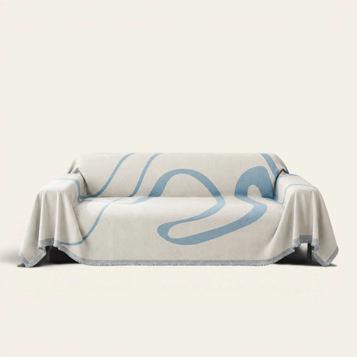 Abstract Muse sofa throw in Azure Flow draped over a couch, front view on ivory background with fringed edges