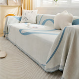 Angled view of the Azure Flow throw draped across a sofa with cushions, book and cup in a sunlit room