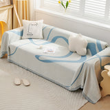 Azure Flow Abstract Muse throw covering a couch by the window with tulips, cushions and slippers on the rug
