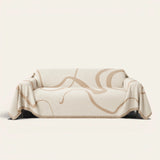 Earth trace Abstract Muse sofa throw draped over a couch, front view on an ivory backdrop with fringe