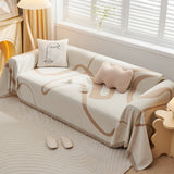 Angled view of the Abstract Muse earth trace throw covering a couch with a boucle cushion and floor lamp