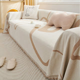 Side angle of the Abstract Muse earth trace throw cascading over a sofa with tan line motifs and fringe