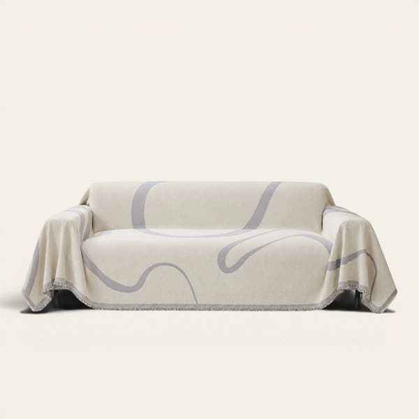 Abstract Muse Monochrome Wave sofa throw draped over a three-seat sofa, front view on ivory