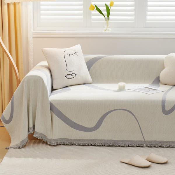 Monochrome Wave Abstract Muse throw styled on a sunlit sofa with a face line-art cushion