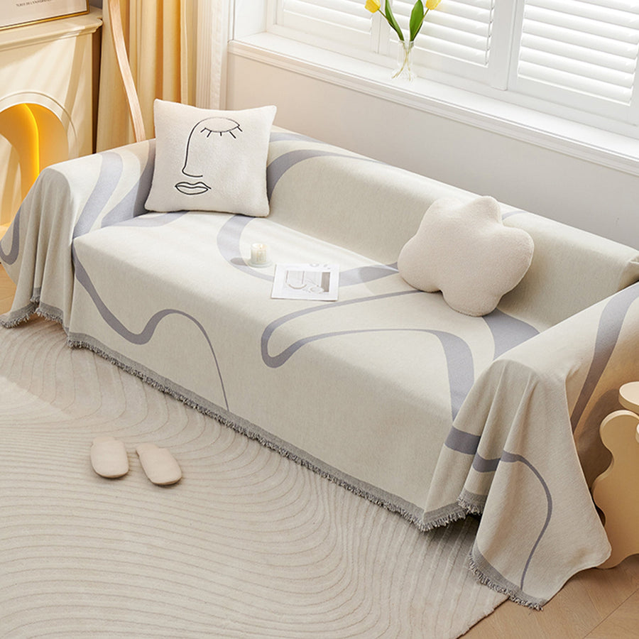 Monochrome Wave Abstract Muse throw covering a sofa with cloud and face cushions, wide view