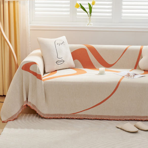 Sunset Stream Abstract Muse throw on a sofa with a line-art face cushion beside tulips