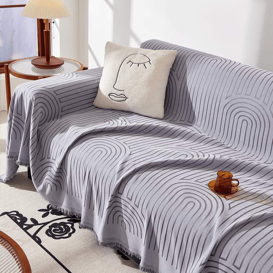 Misty Gray Arcane Ambiance throw styled on a sofa with a face cushion, amber mug and side lamp