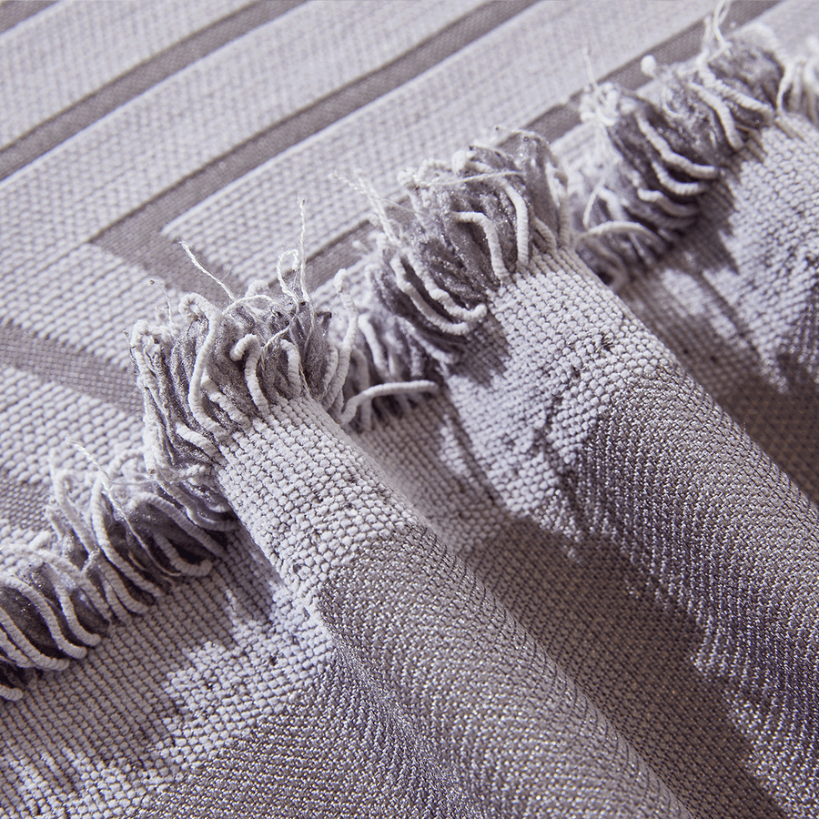 Close-up of Misty Gray Arcane Ambiance fringed edge with tassels and a woven arch motif