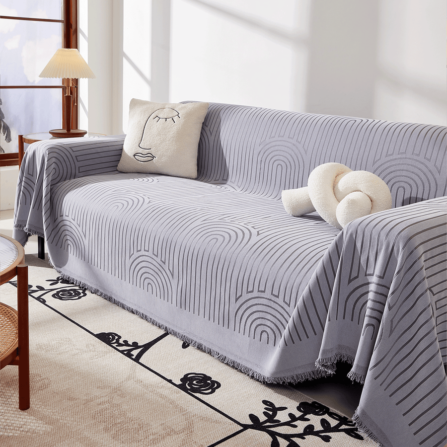 Angled view of Misty Gray Arcane Ambiance throw over a sofa with face and knot cushions