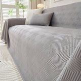 Angled view of the Artisan Cooling graphite mist throw showing its quilted geometric weave on a sofa