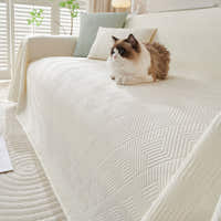 Ivory Cloud Artisan Cooling throw over a sofa with a fluffy cat resting on the textured fabric