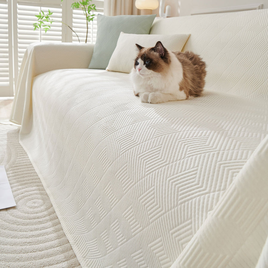 Ivory Cloud Artisan Cooling throw over a sofa with a fluffy cat resting on the textured fabric