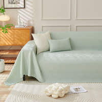 Mint Veil Artisan Cooling throw styled on a sofa with cushions and a plant beside a wooden sideboard