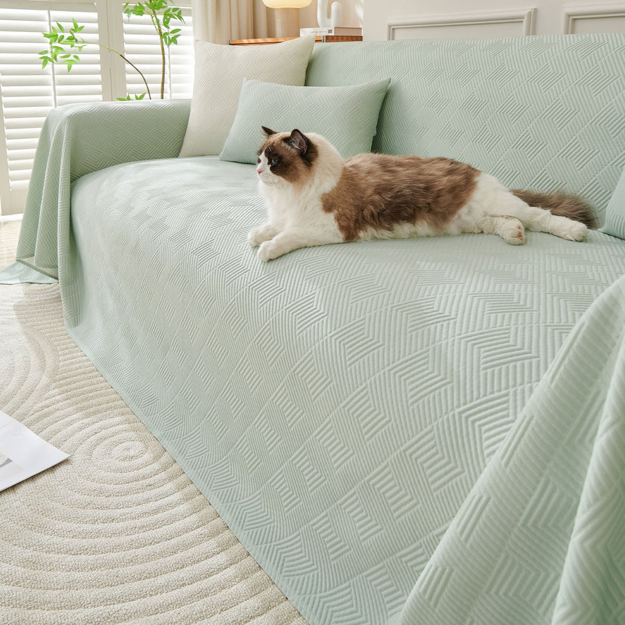 Mint Veil Artisan Cooling throw over a sofa with a fluffy cat resting, cushions and a plant in a bright room