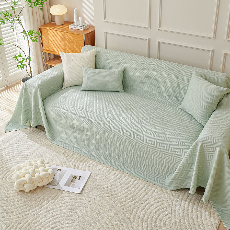 Angled view of Mint Veil Artisan Cooling throw draped over both sofa arms with cushions and a lamp