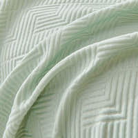 Close-up of Mint Veil Artisan Cooling throw draped, chevron and maze quilted stitching