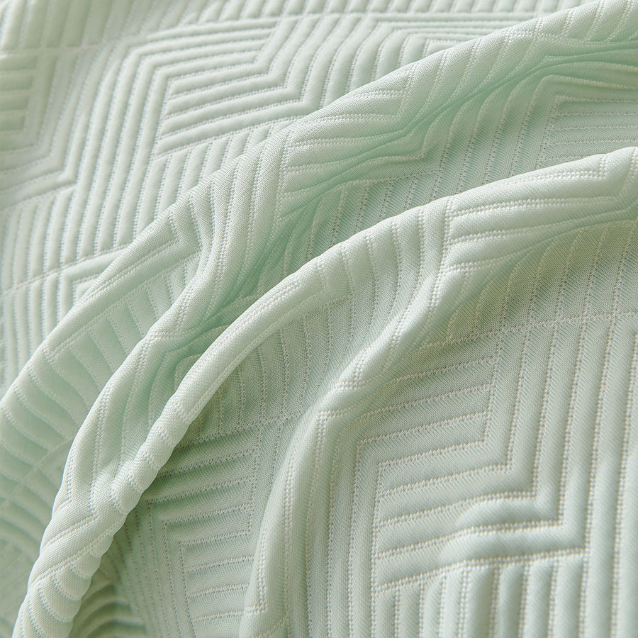 Close-up of Mint Veil Artisan Cooling throw draped, chevron and maze quilted stitching