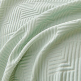 Close-up of Mint Veil Artisan Cooling throw draped, chevron and maze quilted stitching
