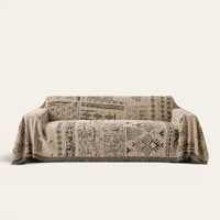 Sand Beige Artisan Glyph throw draped over a two-seat sofa on ivory background